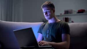 Young veteran on a computer in the dark.